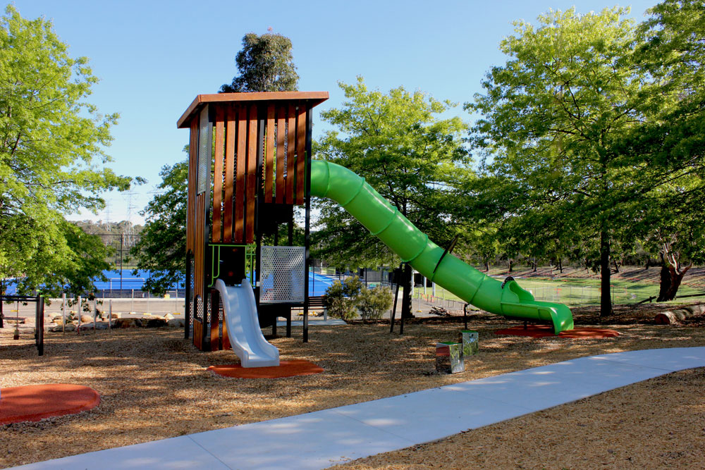 The tall Fortitude Range Rooks Tower at Wantirna Reserve, featuring timber cladding and a long green enclosed slide extending into the playspace.